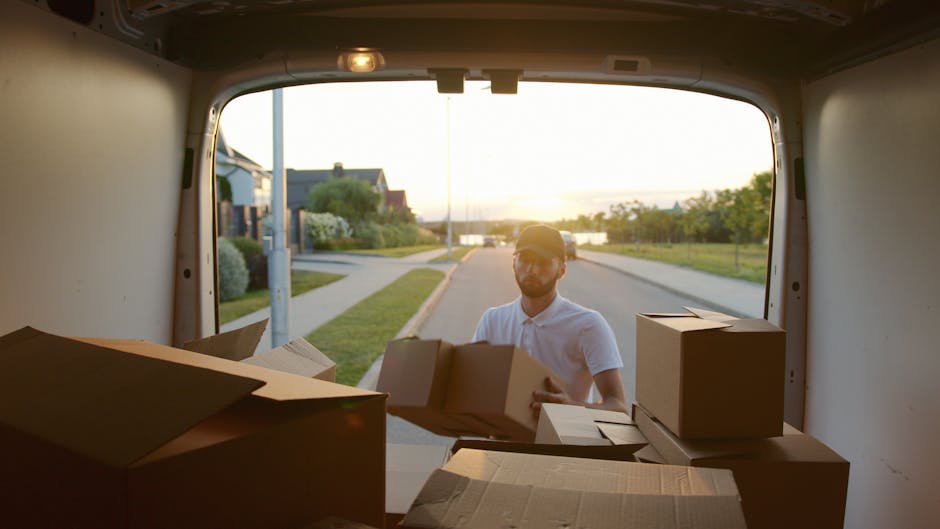 The image shows a white moving van parked on a paved area, with the side panel displaying the text 'MOVING COMPANY' and 'LOCAL & LONG DISTANCE' in bold letters. The vehicle is partially visible, focus